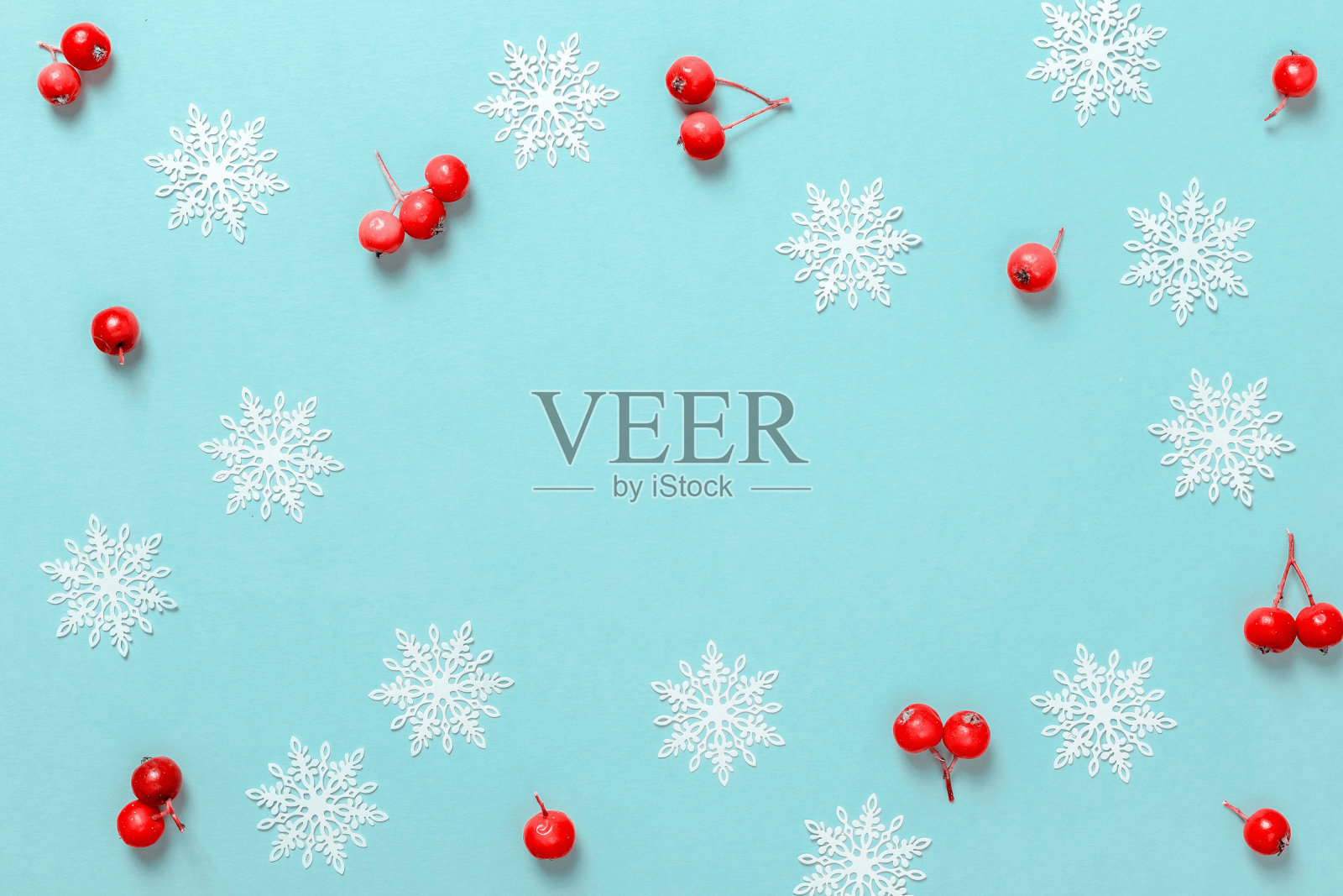 节日圣诞节的背景。白色的雪花，红色的浆果在圣诞节的构图在柔和的蓝色背景贺卡。圣诞节，冬天，新年的概念。照片摄影图片