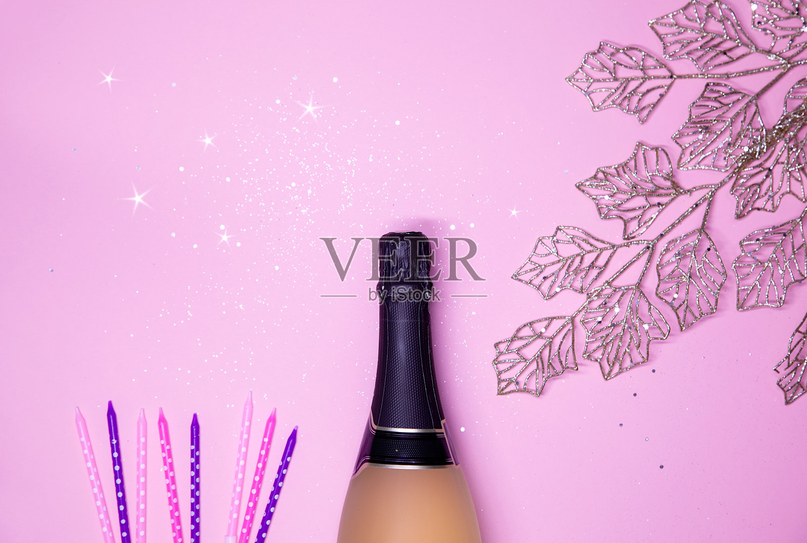 庆典背景为金色的香槟瓶、五彩缤纷的星星、蜡烛和金色的树叶。生日，婚礼或新年的概念。照片摄影图片