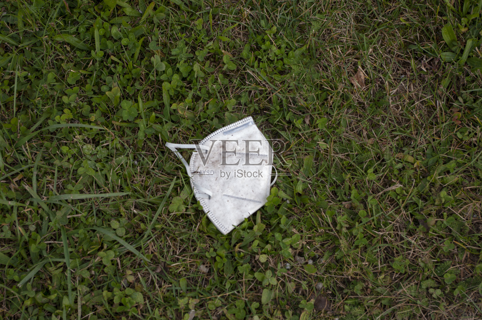 口罩滴在地上草地板，流行病，拯救自然。垃圾。照片摄影图片