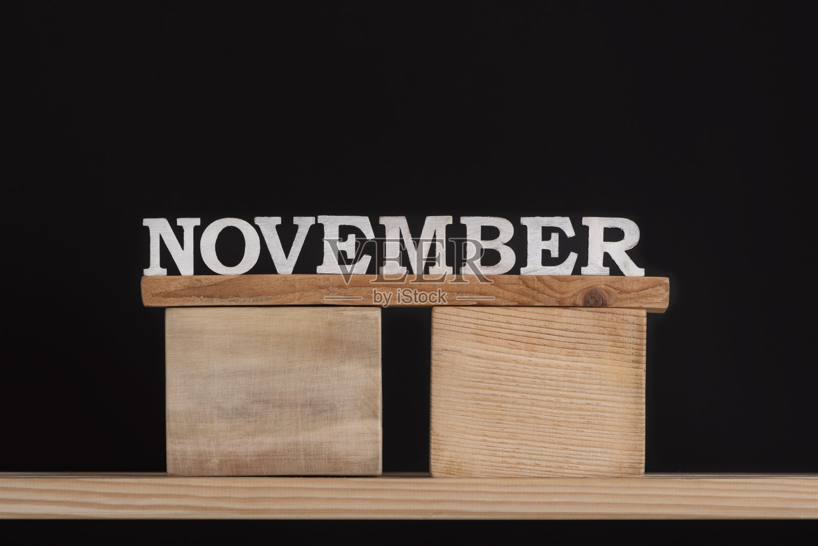在黑色背景上用木头字母写的单词十一月。前视图。秋天的日历。落月照片摄影图片