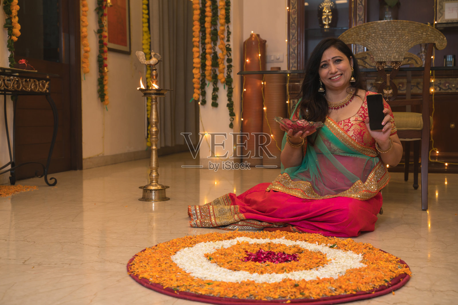 穿着传统服装的妇女坐在地板上展示手机屏幕照片摄影图片