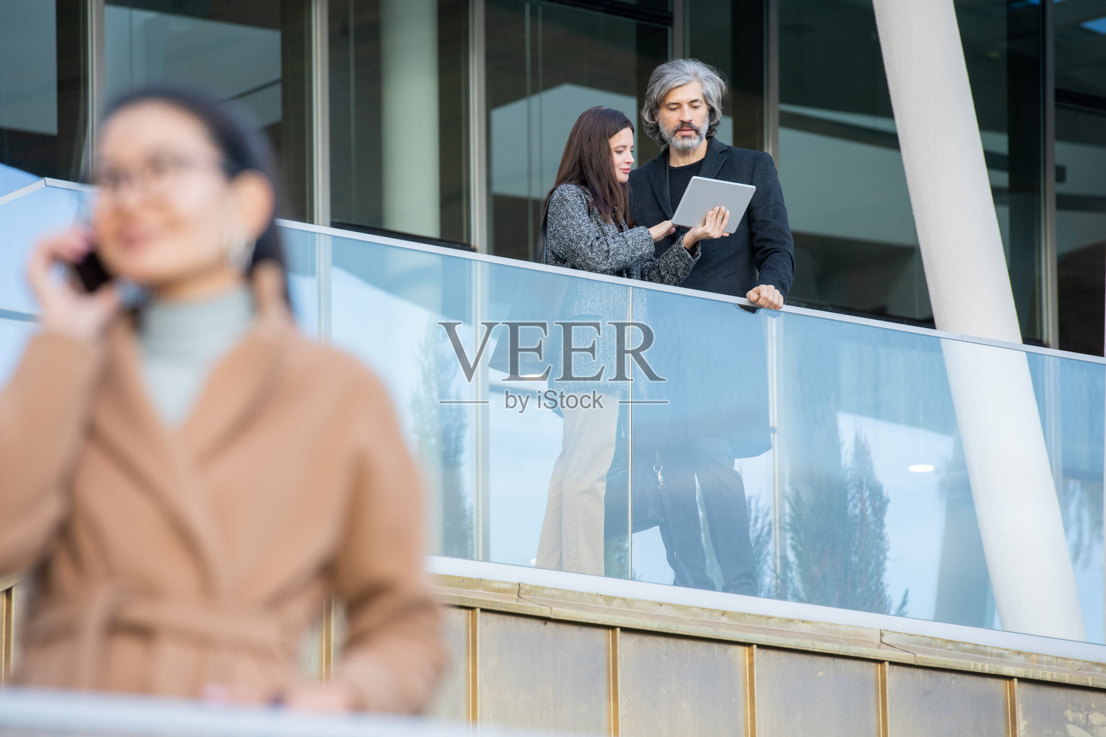 年轻女性用触控板向成熟男性展示财务数据照片摄影图片