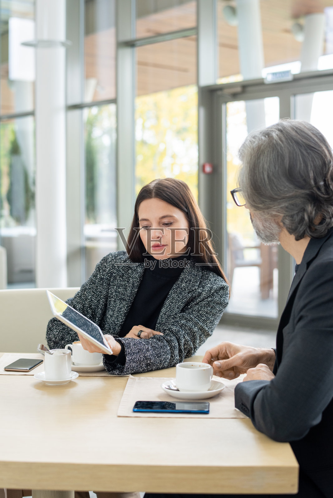 优雅的黑发女商人在展示过程中看着平板电脑照片摄影图片