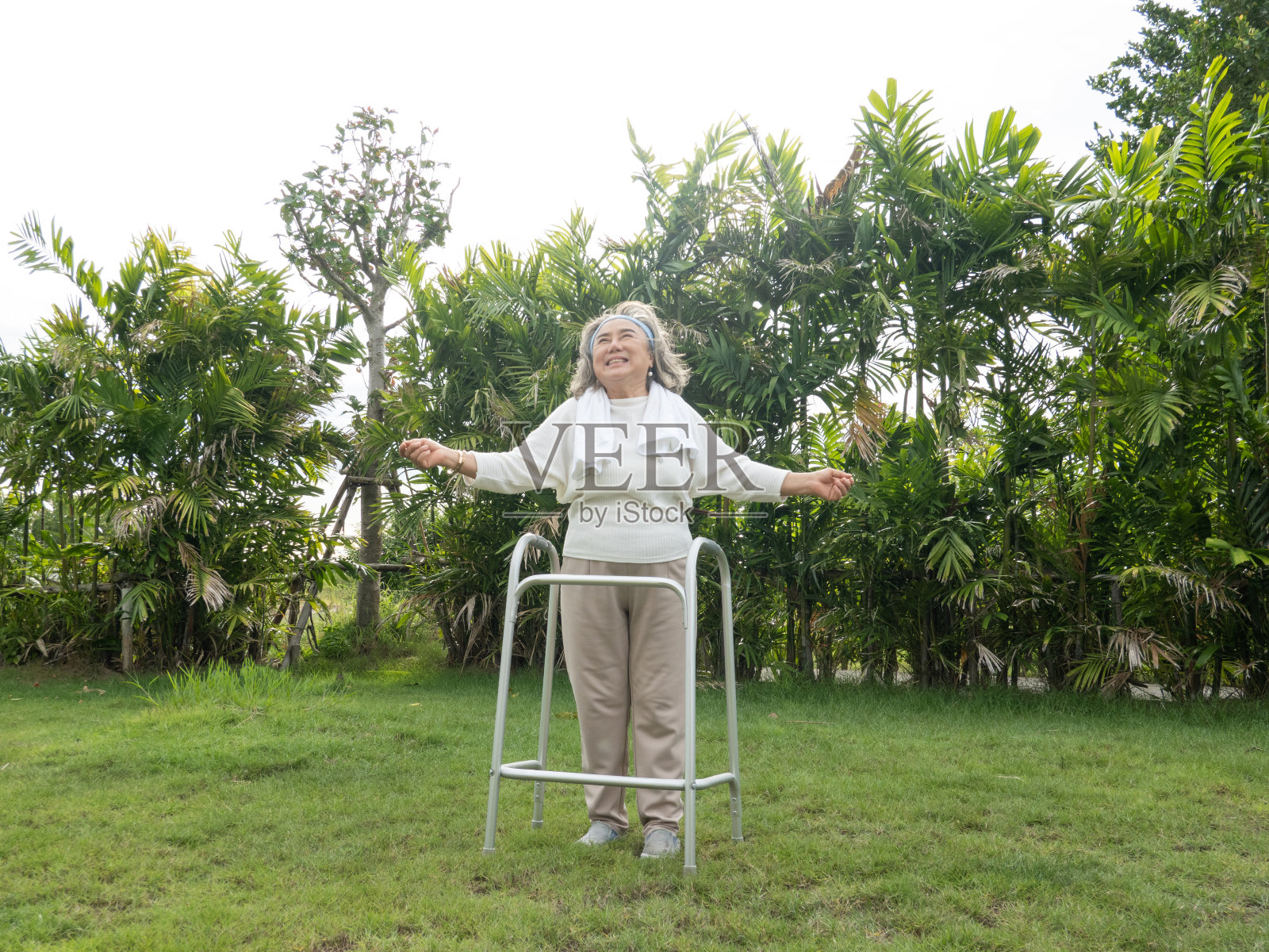 老年妇女在花园里尝试用助行器进行康复锻炼照片摄影图片