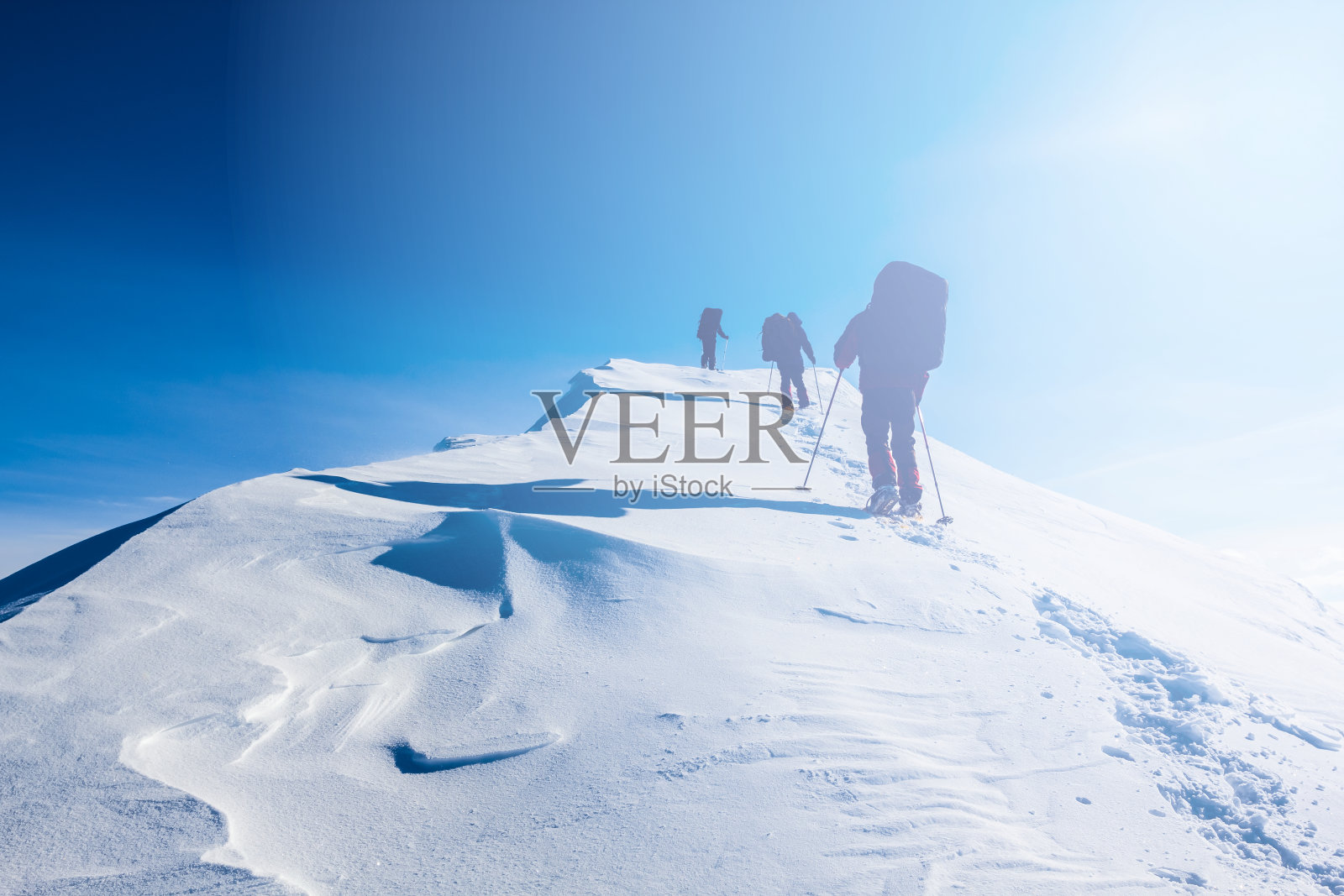 一群徒步旅行者在冬天被雪封住的群山中行走照片摄影图片