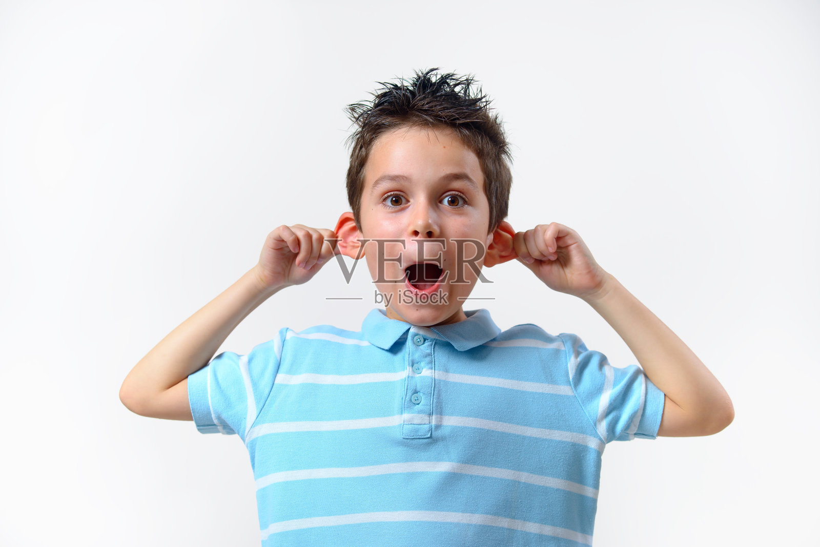 一个穿着蓝色t恤的男孩扮了个鬼脸，把耳朵向两边耷拉，扮成一只猴子。照片摄影图片