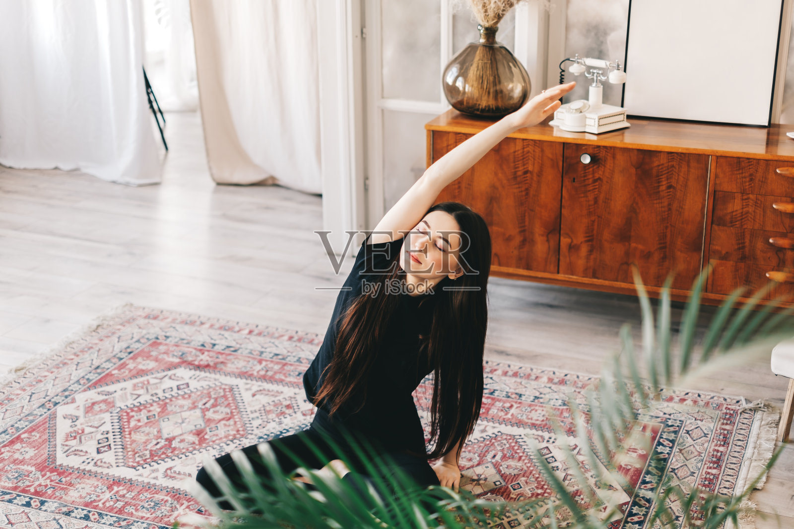 美丽的黑发健身女人做伸展运动，在家里做瑜伽。照片摄影图片