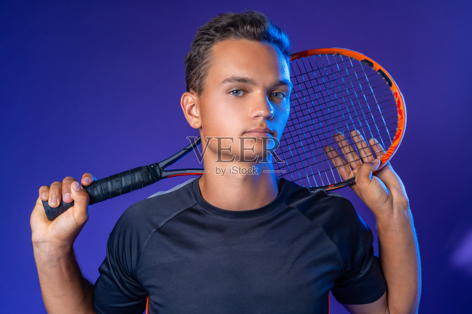 白人年轻男子网球运动员与网球拍在紫色的背景下摆姿势照片摄影图片