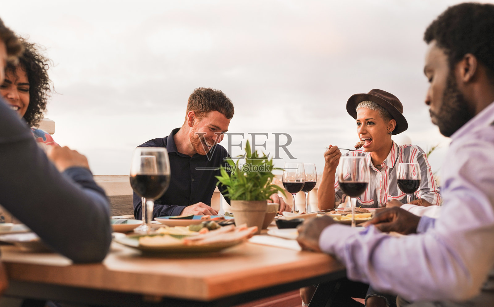 多种族的朋友们一起在户外的露台上享用晚餐照片摄影图片
