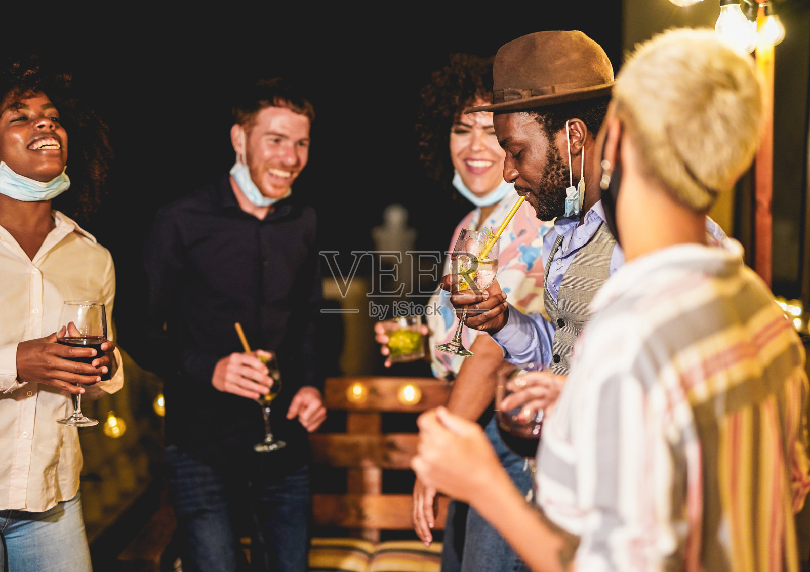 欢快的多种族的人们在下巴下戴着外科口罩一起跳舞-家庭私人聚会照片摄影图片