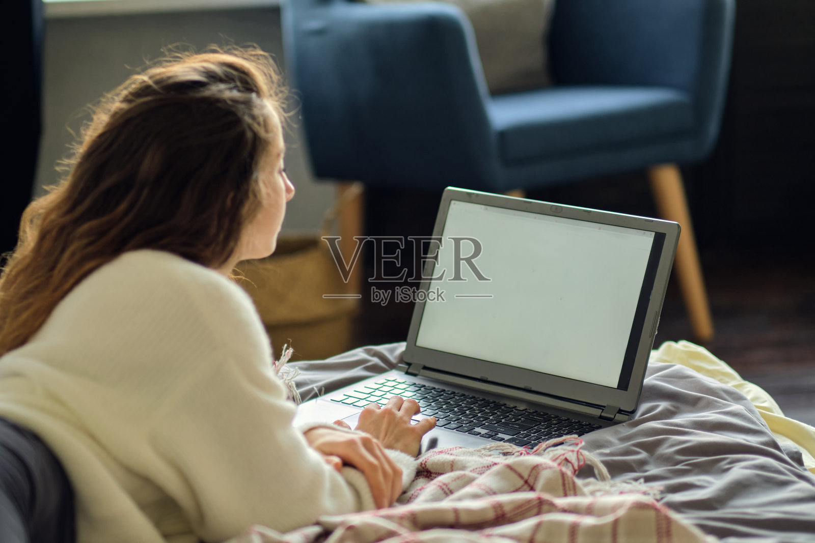 一个快乐随意的漂亮女人坐在家里的床上用笔记本电脑工作照片摄影图片