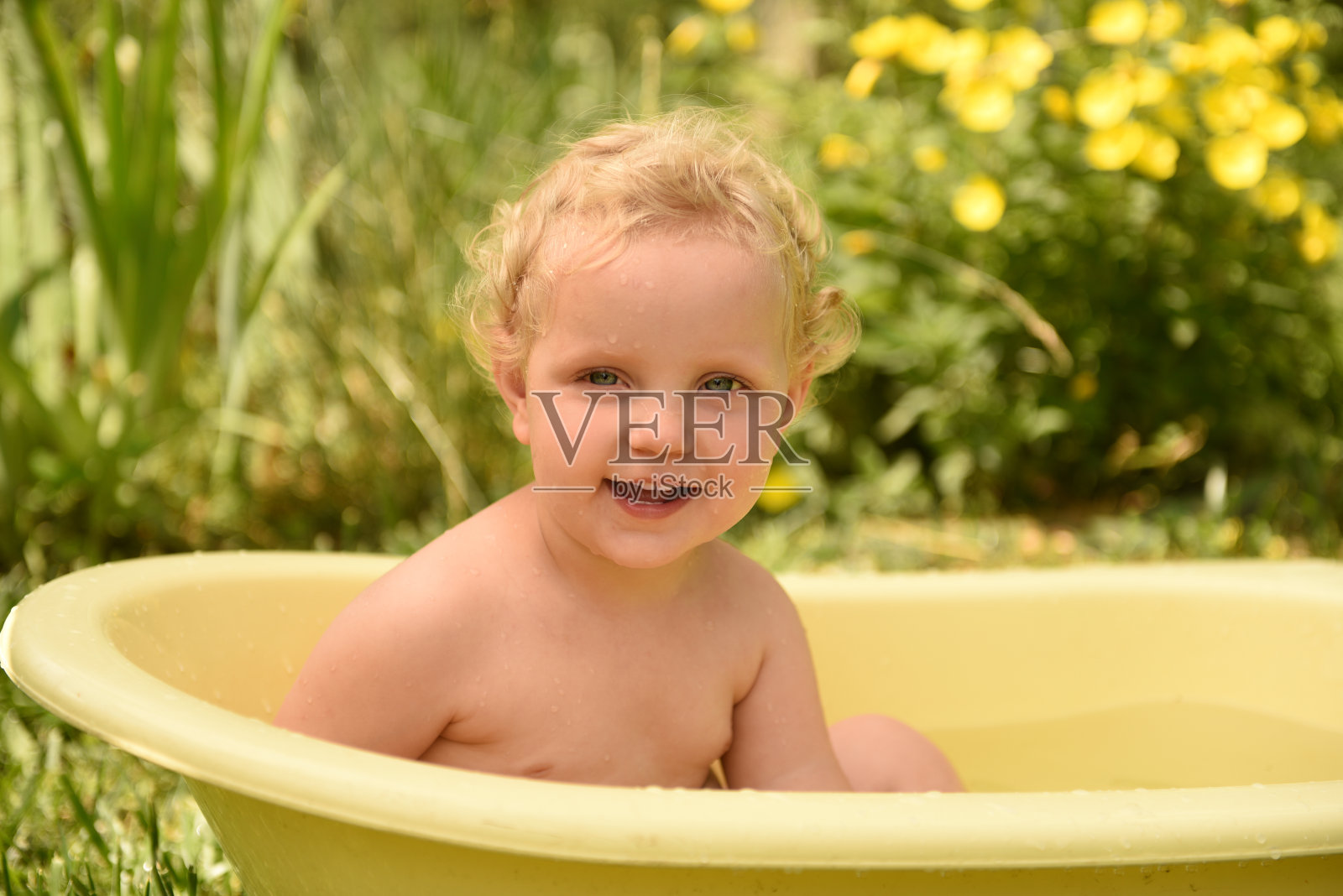 小女孩在院子里洗澡玩得很开心。照片摄影图片