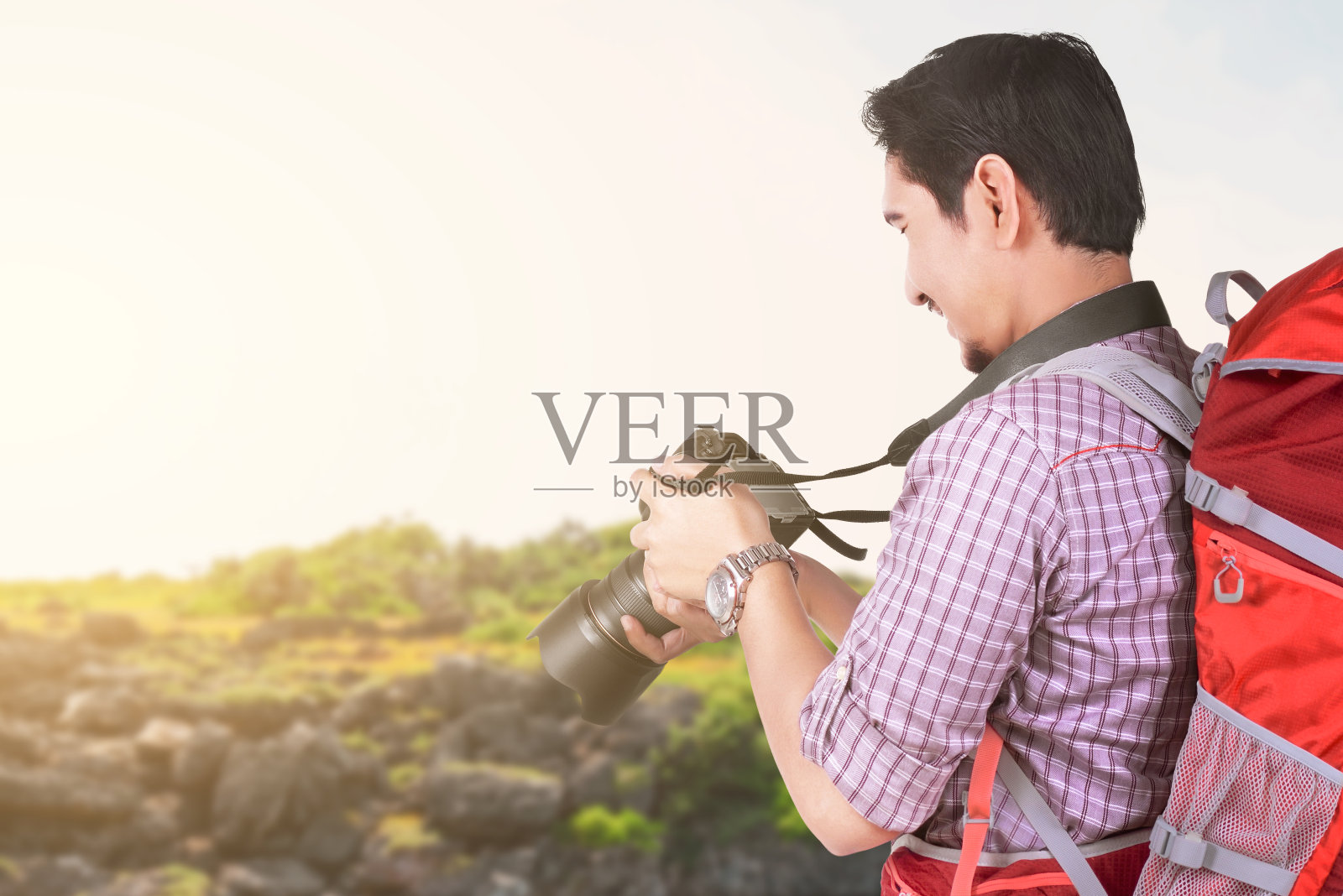亚洲男子与一个背包，拿着相机与湖景和蓝天背景照片摄影图片