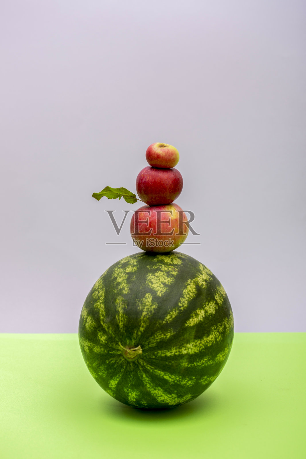 成熟的西瓜和三个苹果在彩色的背景上照片摄影图片