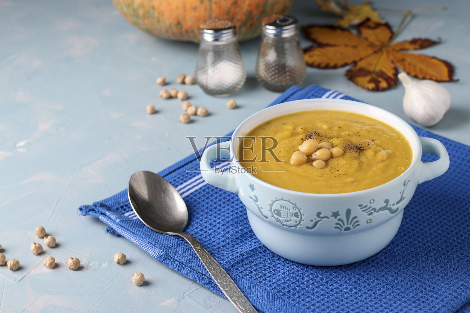 素食秋季南瓜奶油汤与鹰嘴豆在浅蓝色的背景，特写照片摄影图片