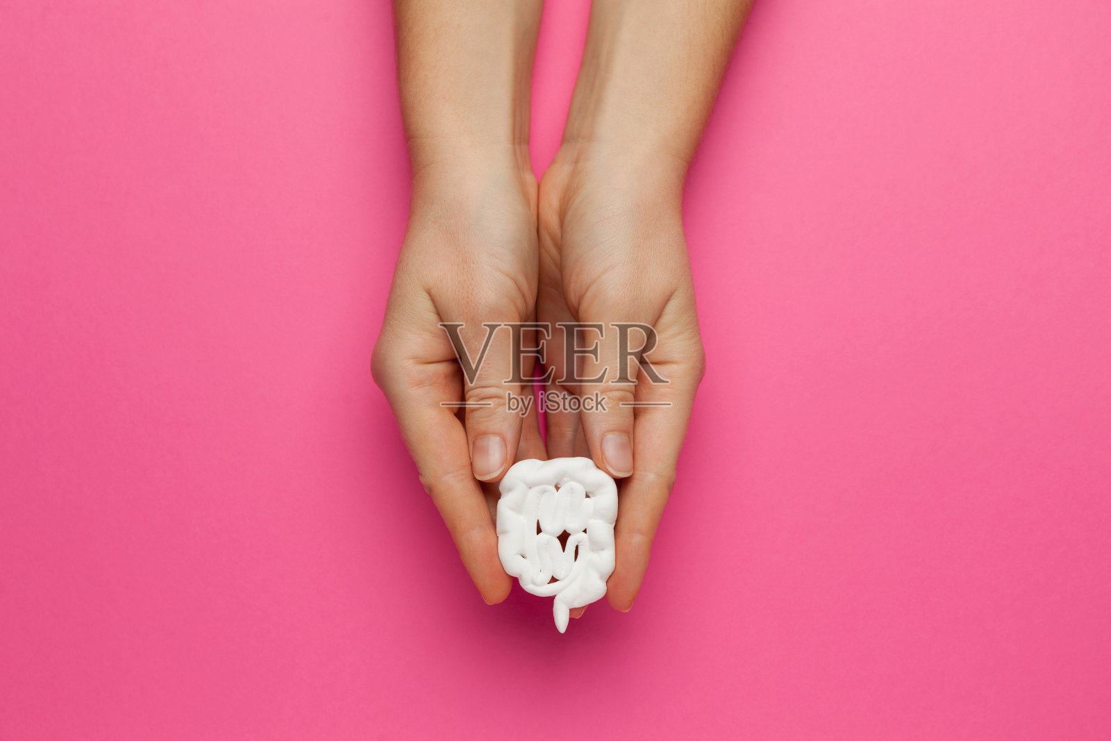 肠子和手放在粉红色的背景上。胃肠道炎症。消化疼痛，治疗生态失调。益生菌。照片摄影图片