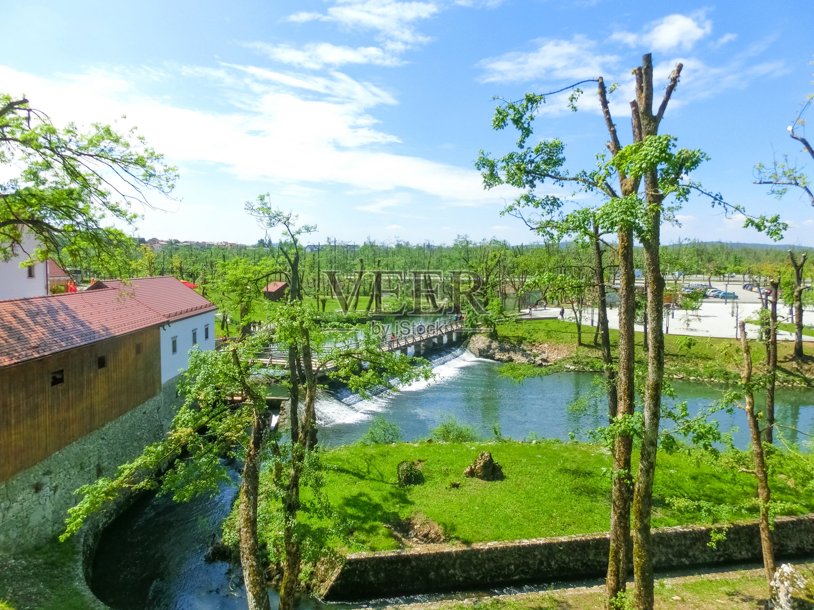 在Postojna洞穴附近的公园Postojna jama，可以看到瀑布，白色建筑中的磨坊，人行桥照片摄影图片