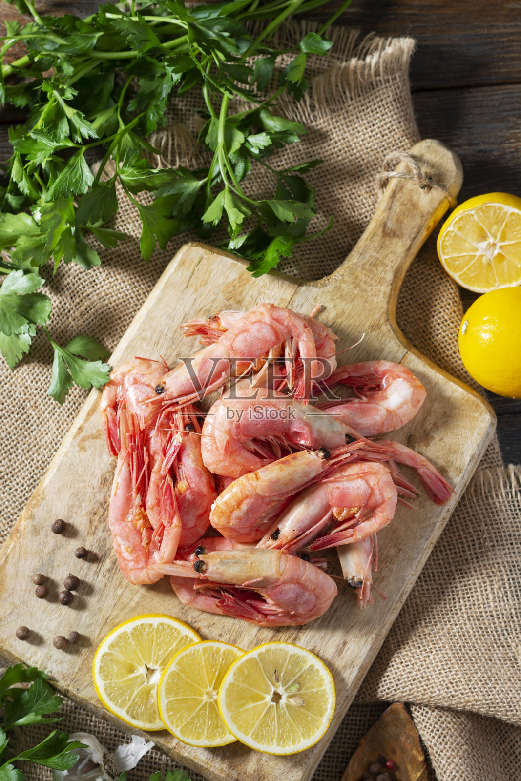 生鲜虾放在一块木板上，放在棕色的木桌上。乡村风格。顶部视图与复制空间照片摄影图片