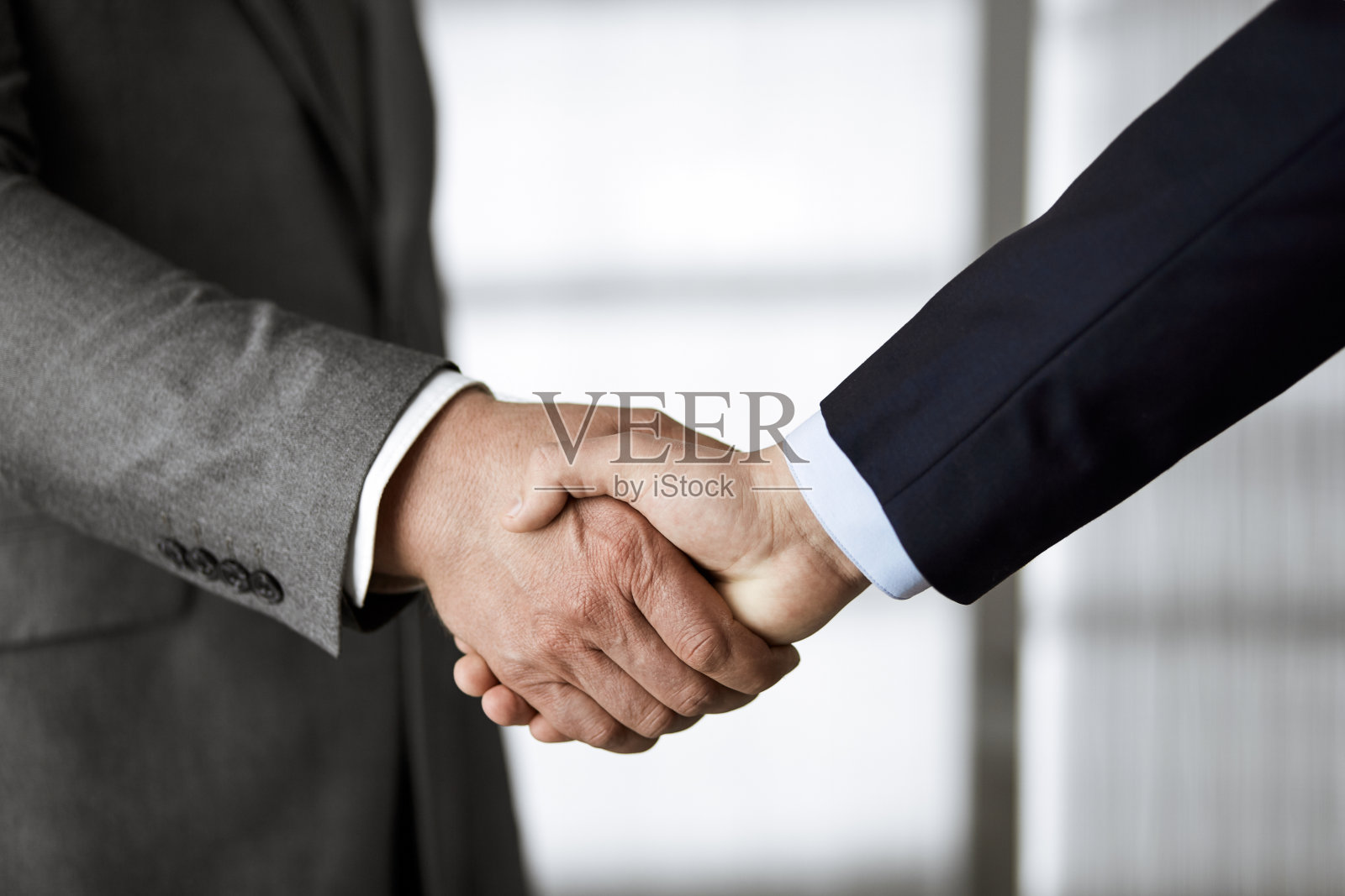 商务人士穿着西装站着握手，特写。商务沟通的概念。握手和营销照片摄影图片