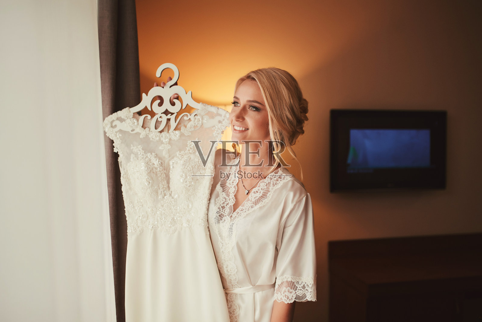 手里拿着婚纱的年轻新娘。可爱的新娘。新娘的早晨照片摄影图片