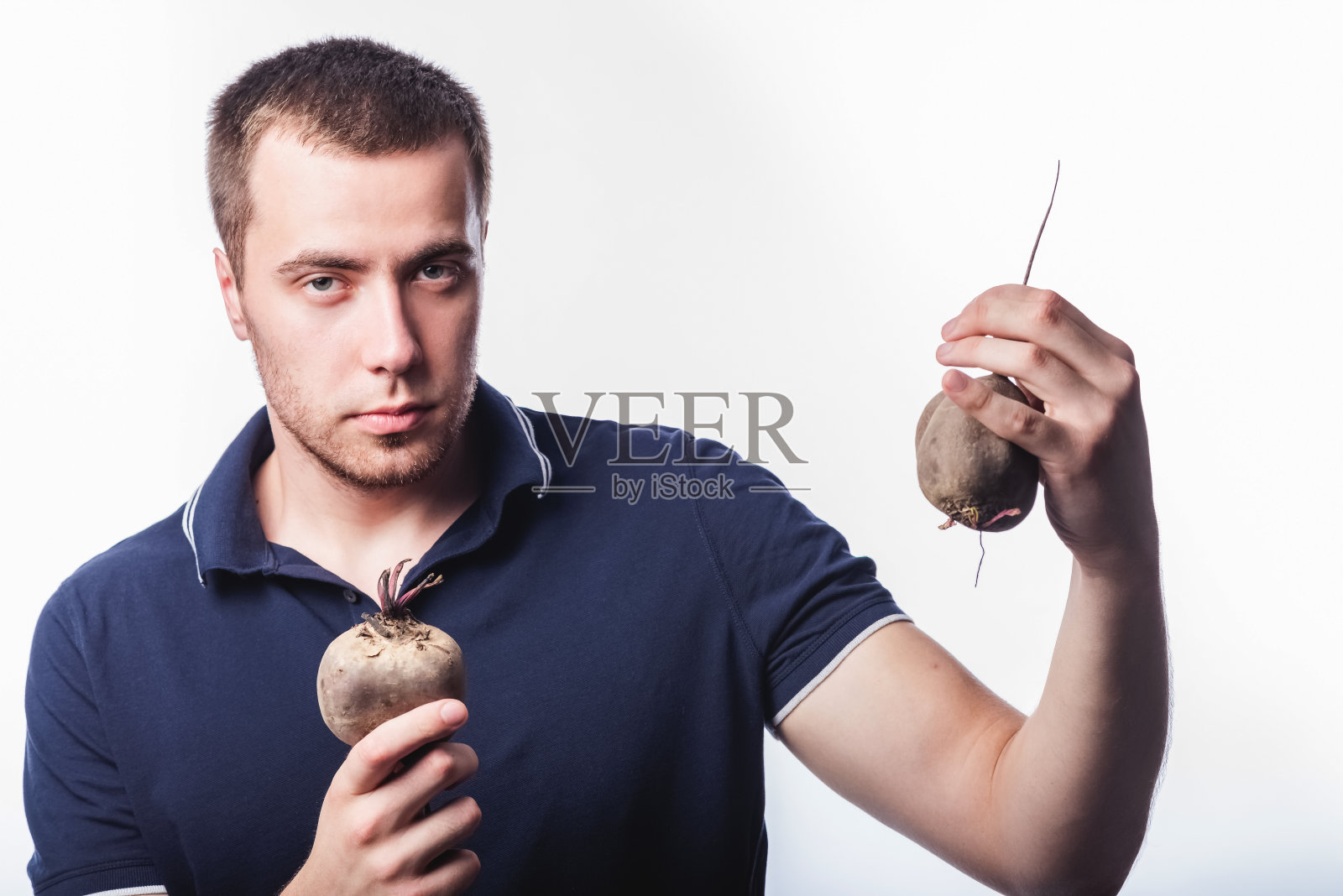 一个在灰色背景上往画室里扔蔬菜的帅哥的肖像。适当营养的概念照片摄影图片