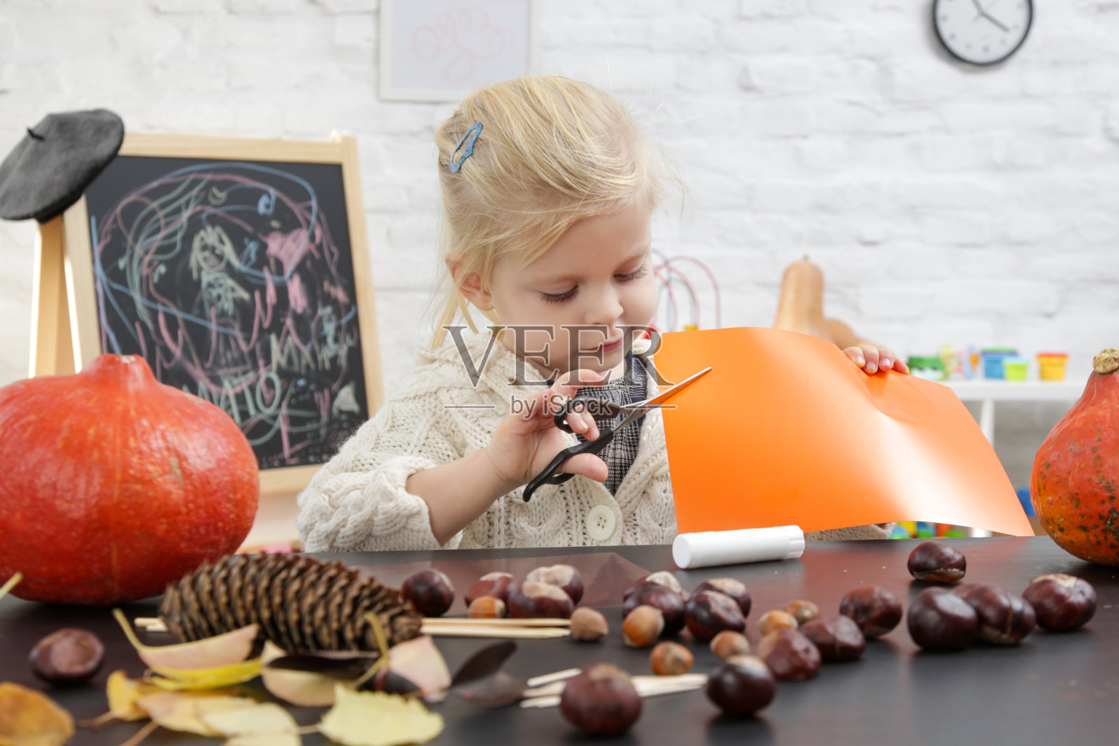 可爱的小女孩在玩万圣节的装饰品。秋季在家DIY工艺。照片摄影图片
