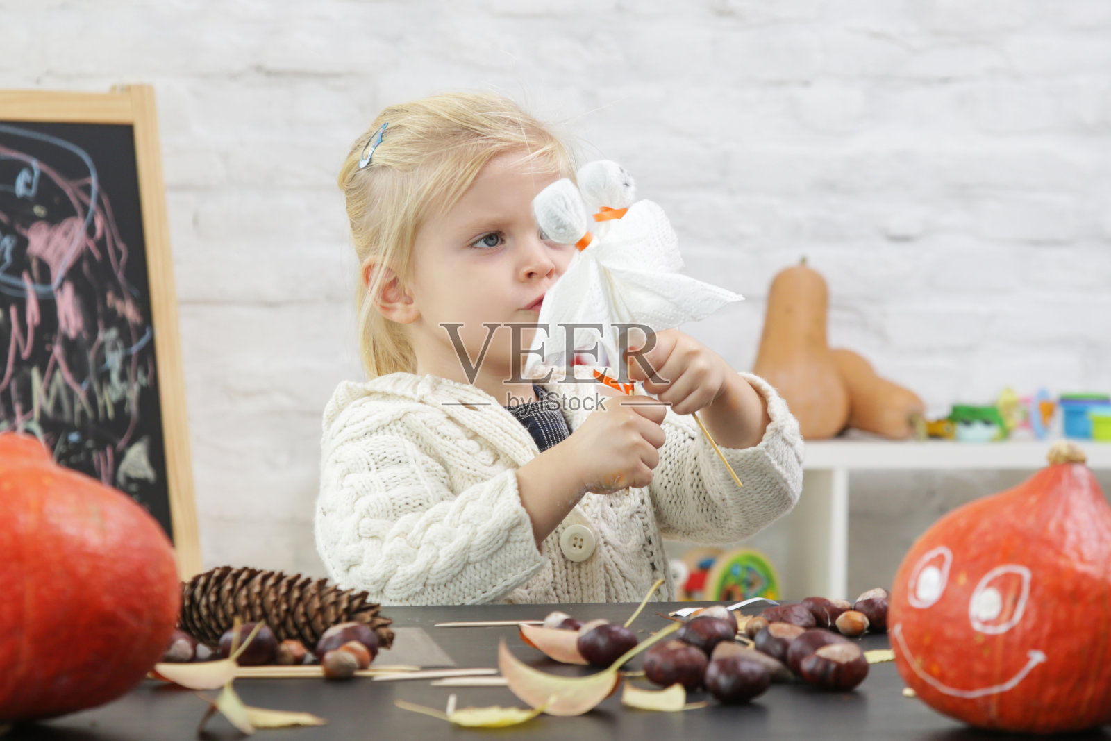 可爱的小女孩在玩万圣节的装饰品。秋季在家DIY工艺。照片摄影图片