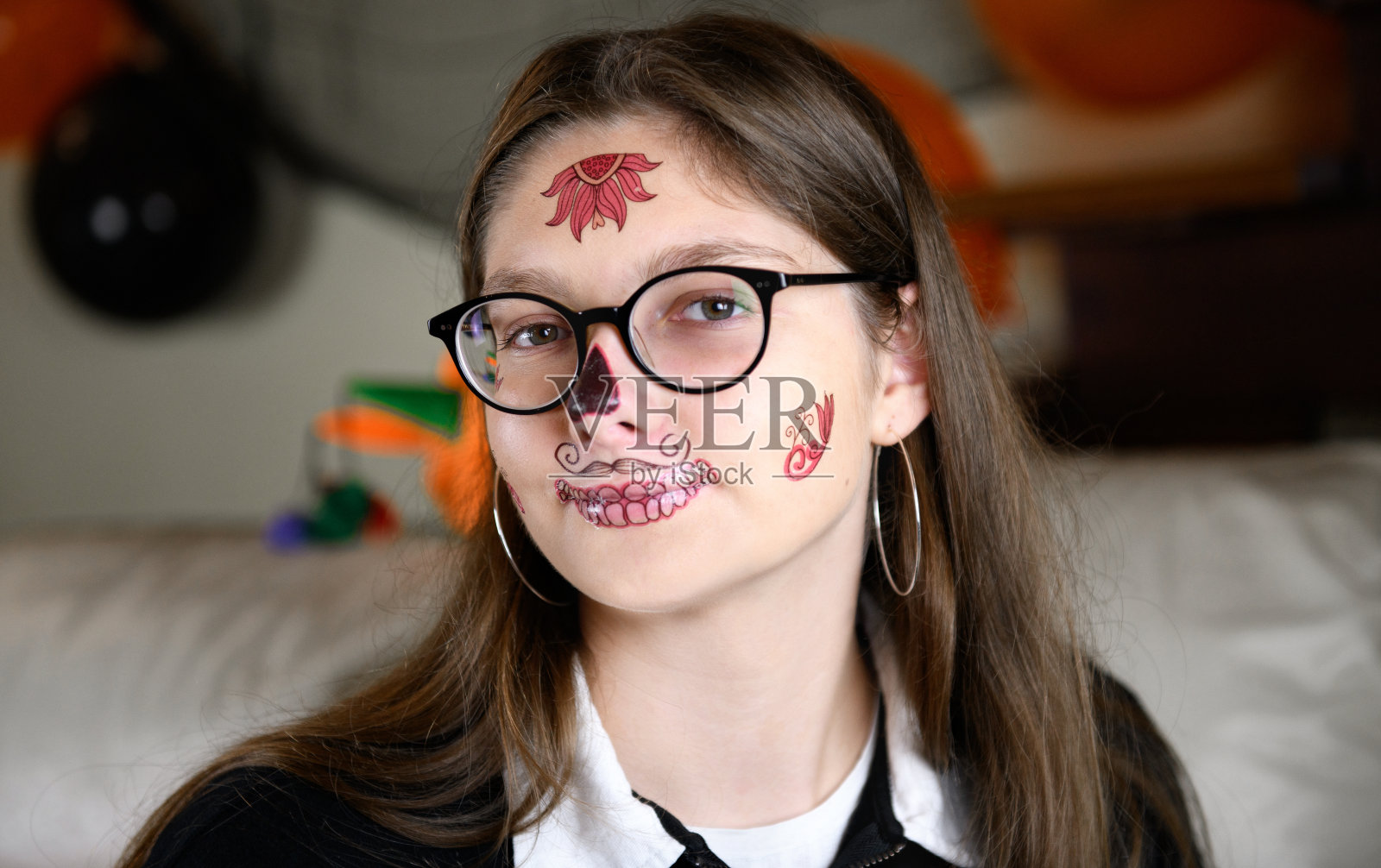 一个女孩展示她自己万圣节化妆的死亡圣或糖墨西哥头骨。在家庆祝万圣节照片摄影图片
