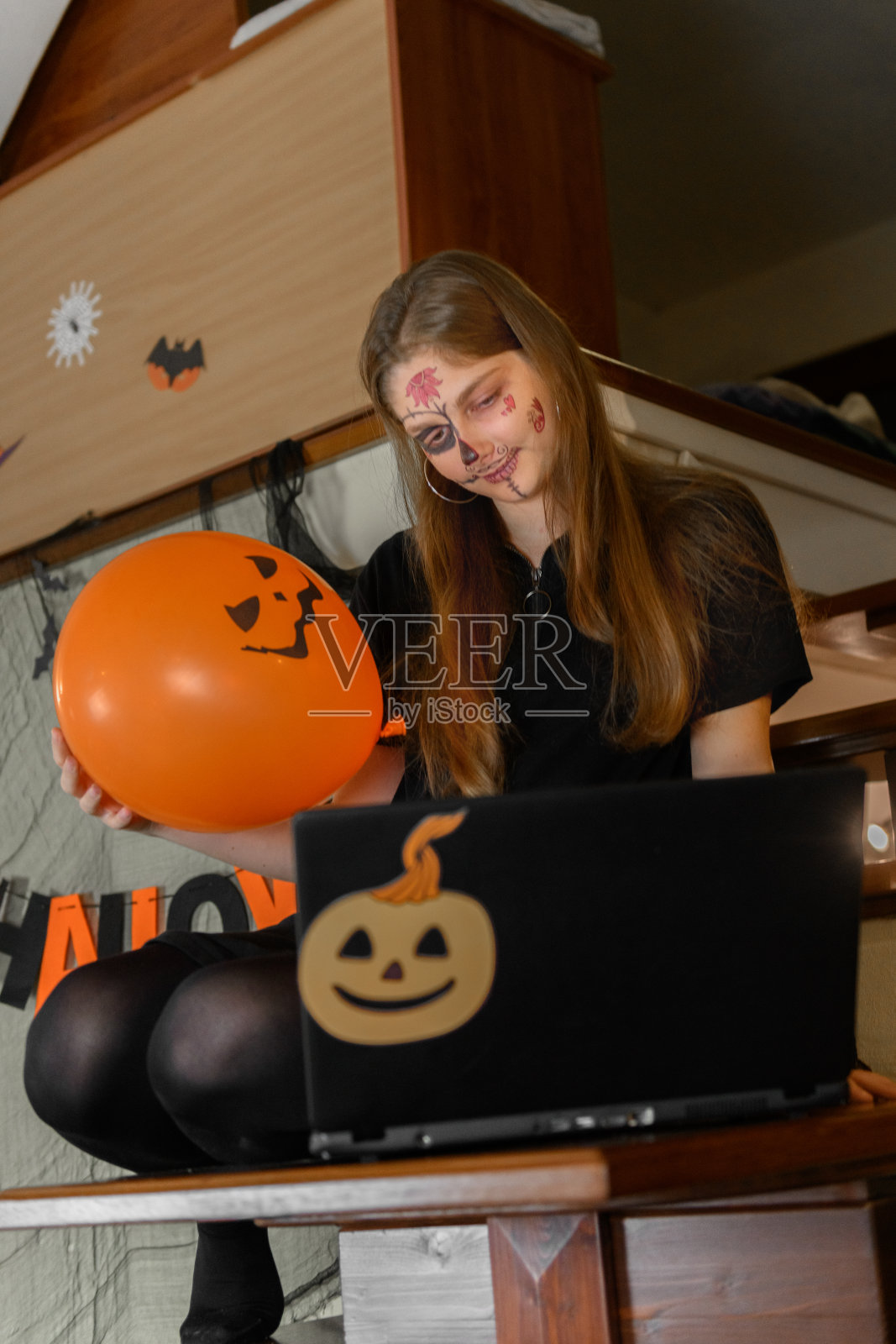 万圣节化妆的女孩通过笔记本电脑视频电话祝贺她的朋友和家人照片摄影图片