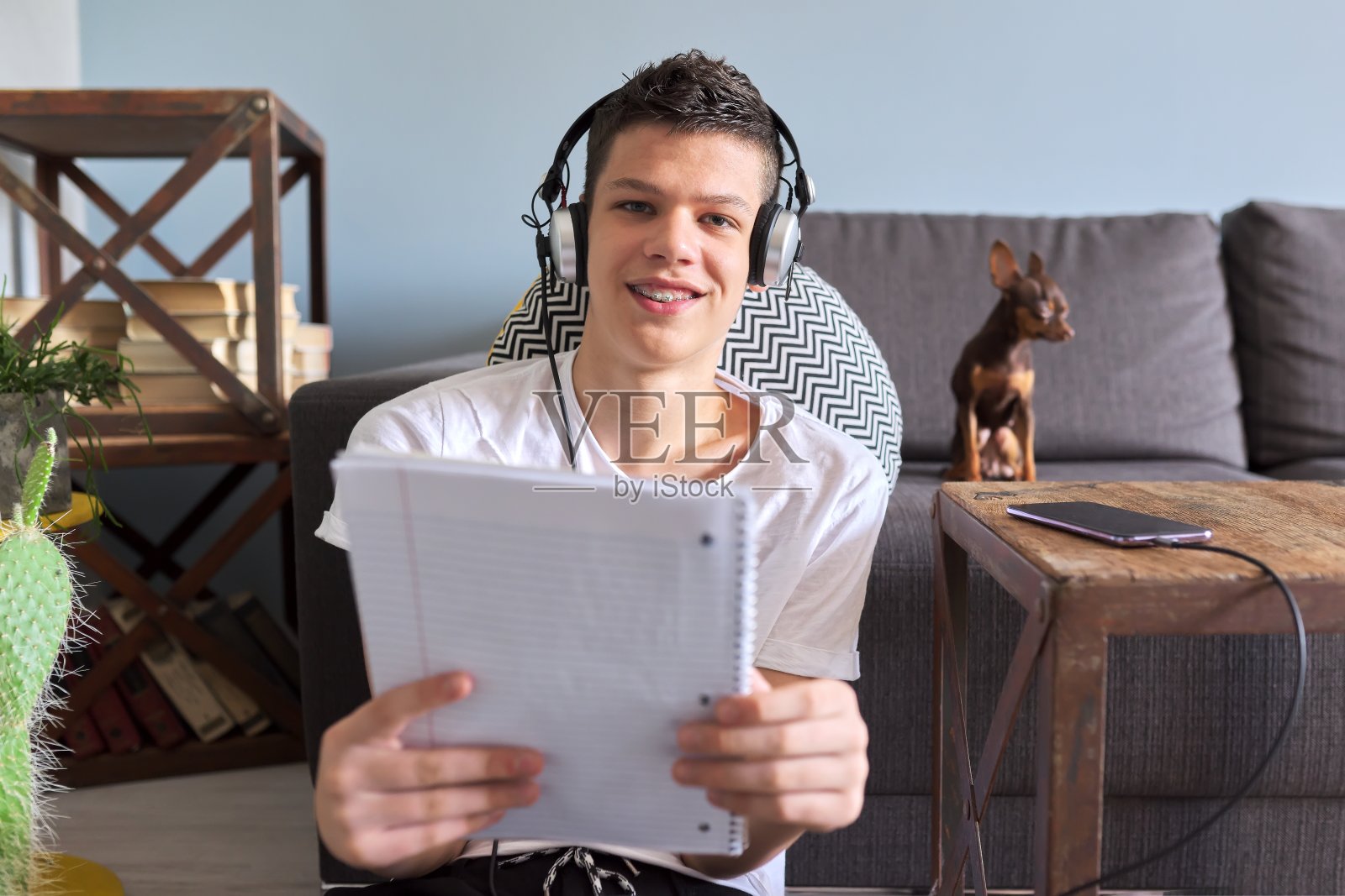 十几岁的学生戴着耳机，用笔记本和智能手机学习照片摄影图片