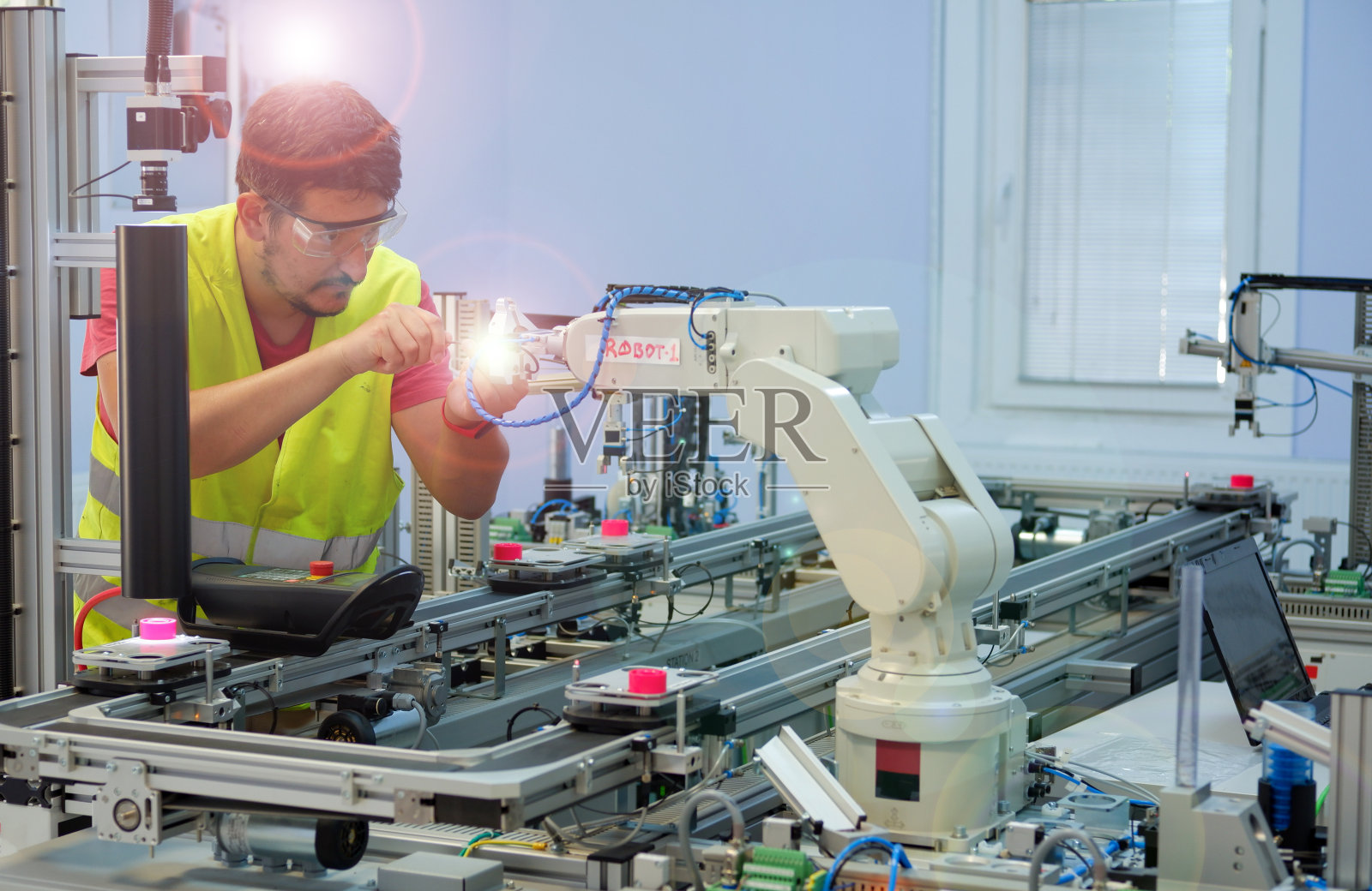 戴着安全眼镜的维修工程师(机械师)在技术实验室修理机器人手臂。照片摄影图片