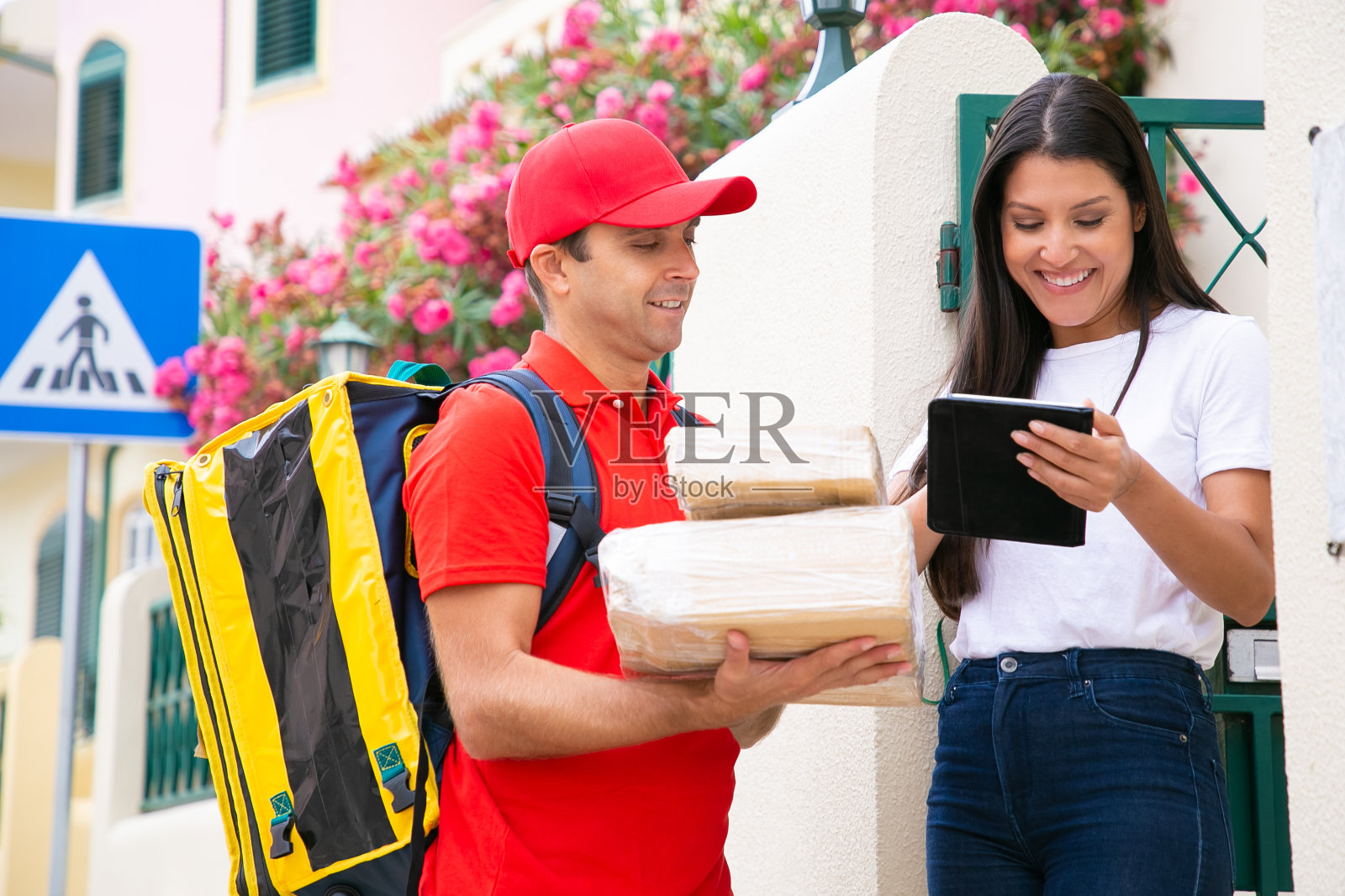 快乐的快递员拿着平板电脑站在顾客旁边照片摄影图片