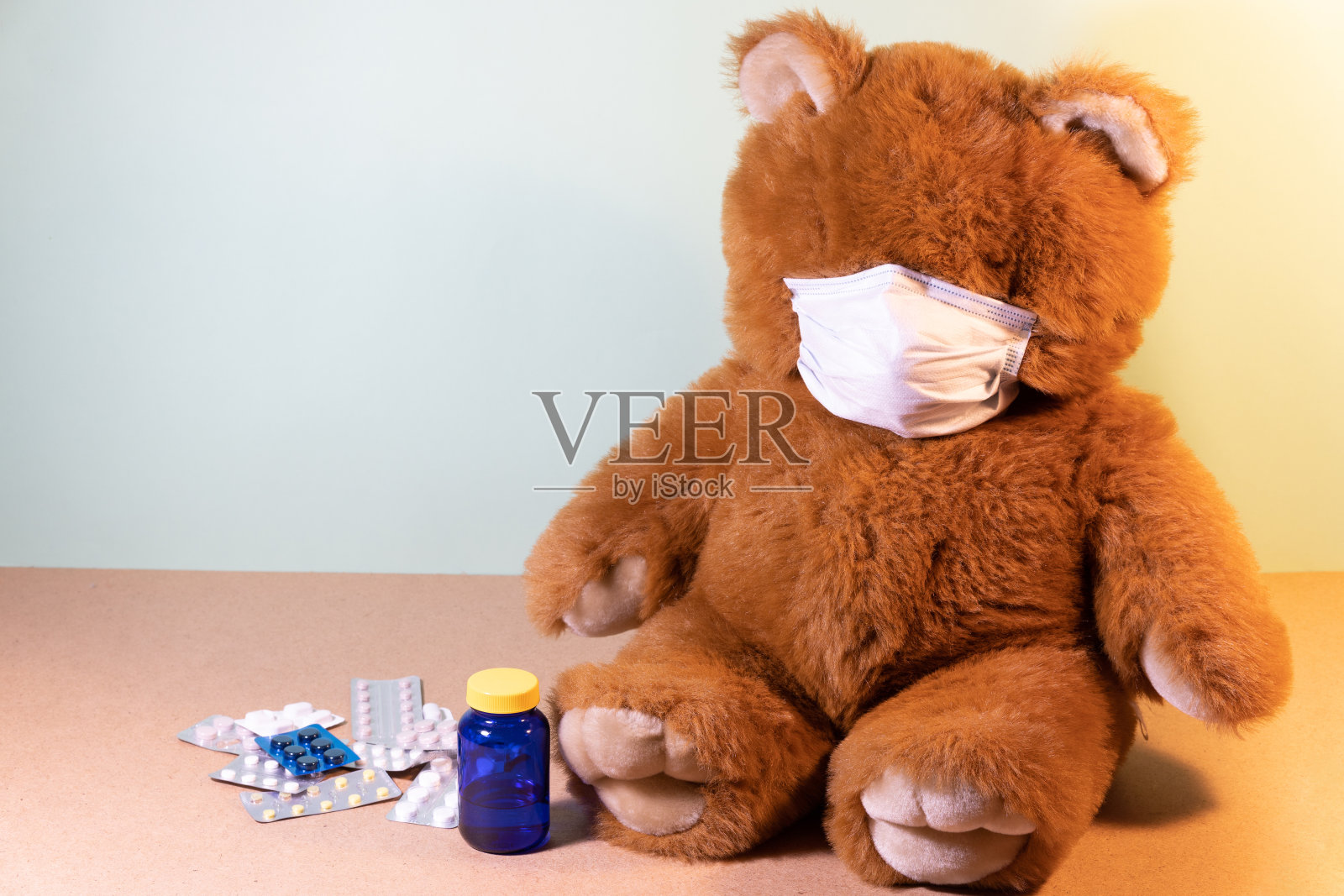 泰迪熊戴着防护面具，周围有许多包药。隔离和治愈时间。呆在家里。照片摄影图片