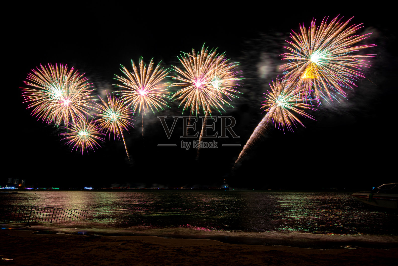 在庆祝之夜，令人惊叹的美丽多彩的烟花表演，展现在海滩上的多色倒影的水照片摄影图片