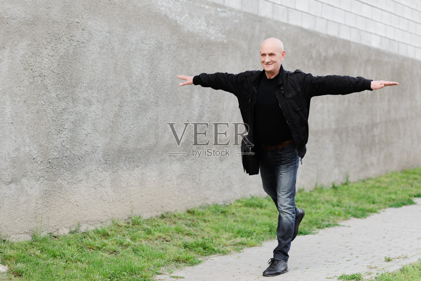 一位老人伸出双手站在混凝土背景上照片摄影图片