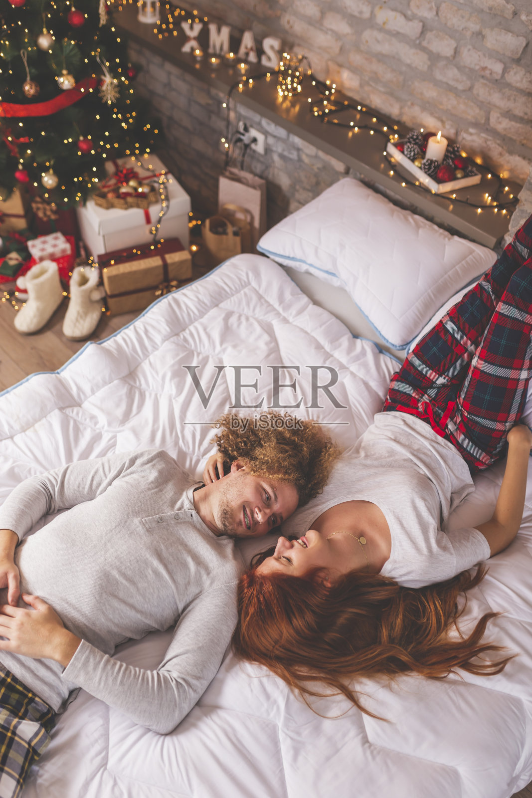 一对夫妇在圣诞节的早晨倒挂在床上照片摄影图片