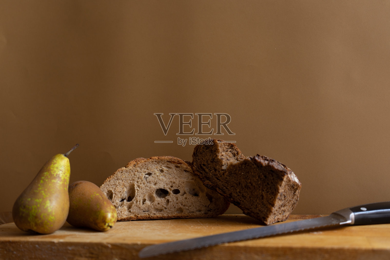 新鲜烤的加利西亚面包，配时令梨，木板上，棕色背景照片摄影图片