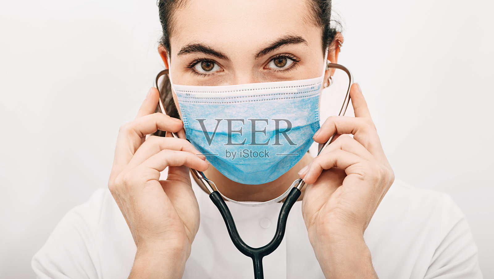 一位经验丰富的医生在医院工作时戴着防护面具和听诊器。大流行、冠状病毒、病毒防护。在白色背景照片摄影图片