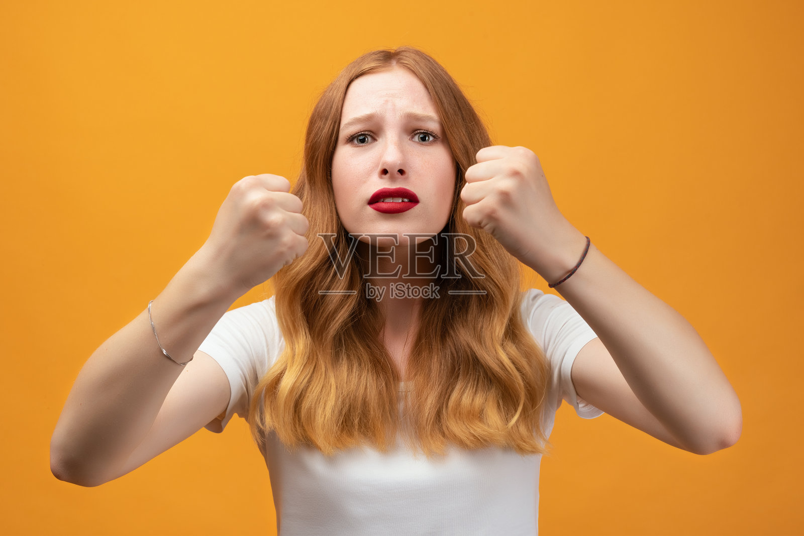 漂亮的女孩，红发波浪，举起拳头沮丧和愤怒照片摄影图片