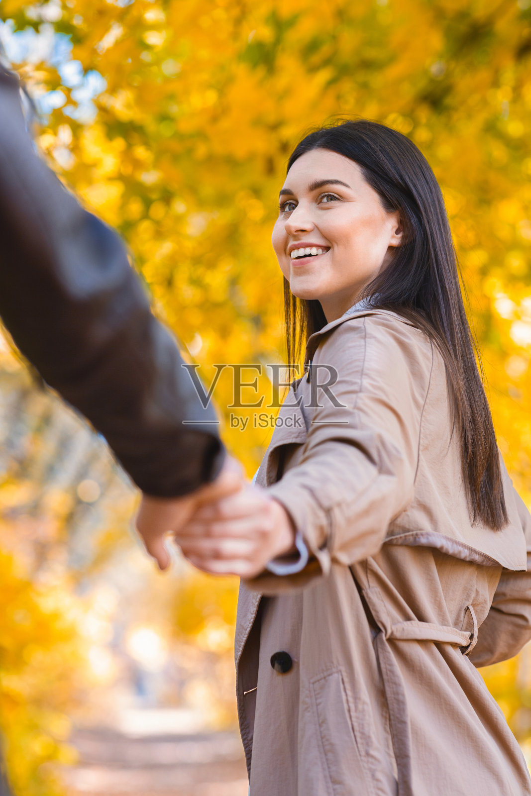 情绪化的年轻女子拉着她男人的手，走过森林照片摄影图片