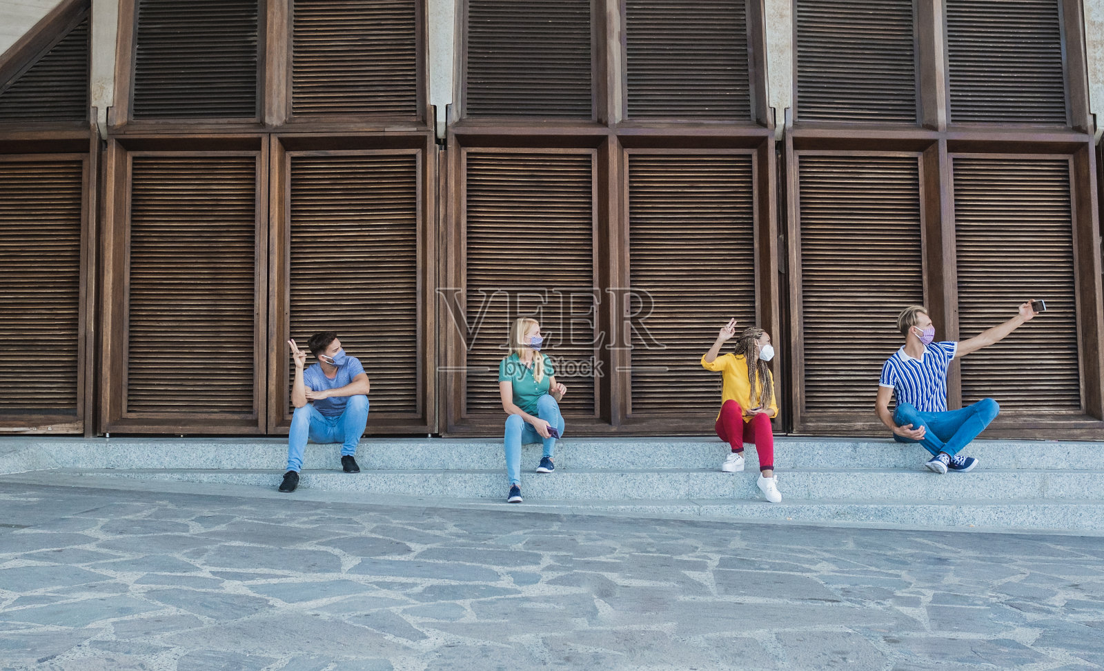 快乐的多种族朋友们戴着防护口罩玩得开心并自拍——社交距离和冠状病毒生活方式的概念照片摄影图片