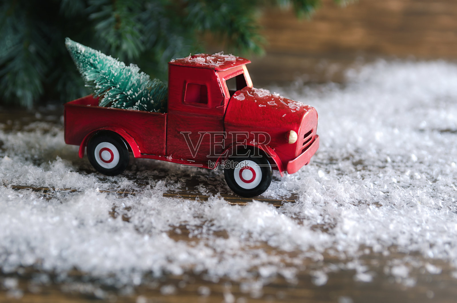 一辆红色的汽车载着一棵圣诞冷杉树在雪地的背景下。圣诞和寒假的概念。照片摄影图片