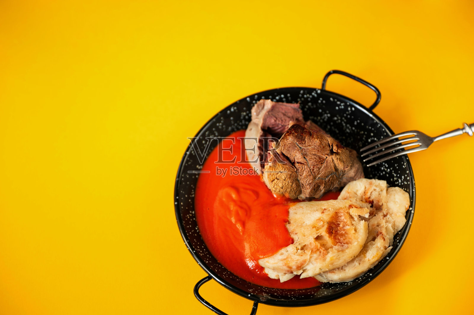 牛膝，番茄酱和饺子放在黑色的平底锅上。照片摄影图片