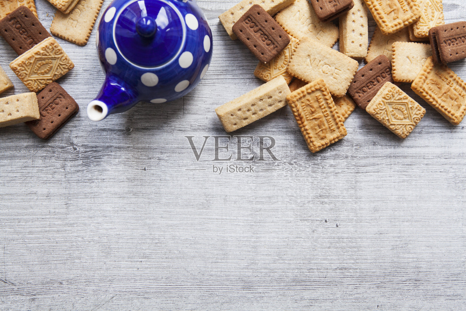 一排经典的英国饼干与茶壶在粗糙的木制背景与复制空间直接向上观看照片摄影图片