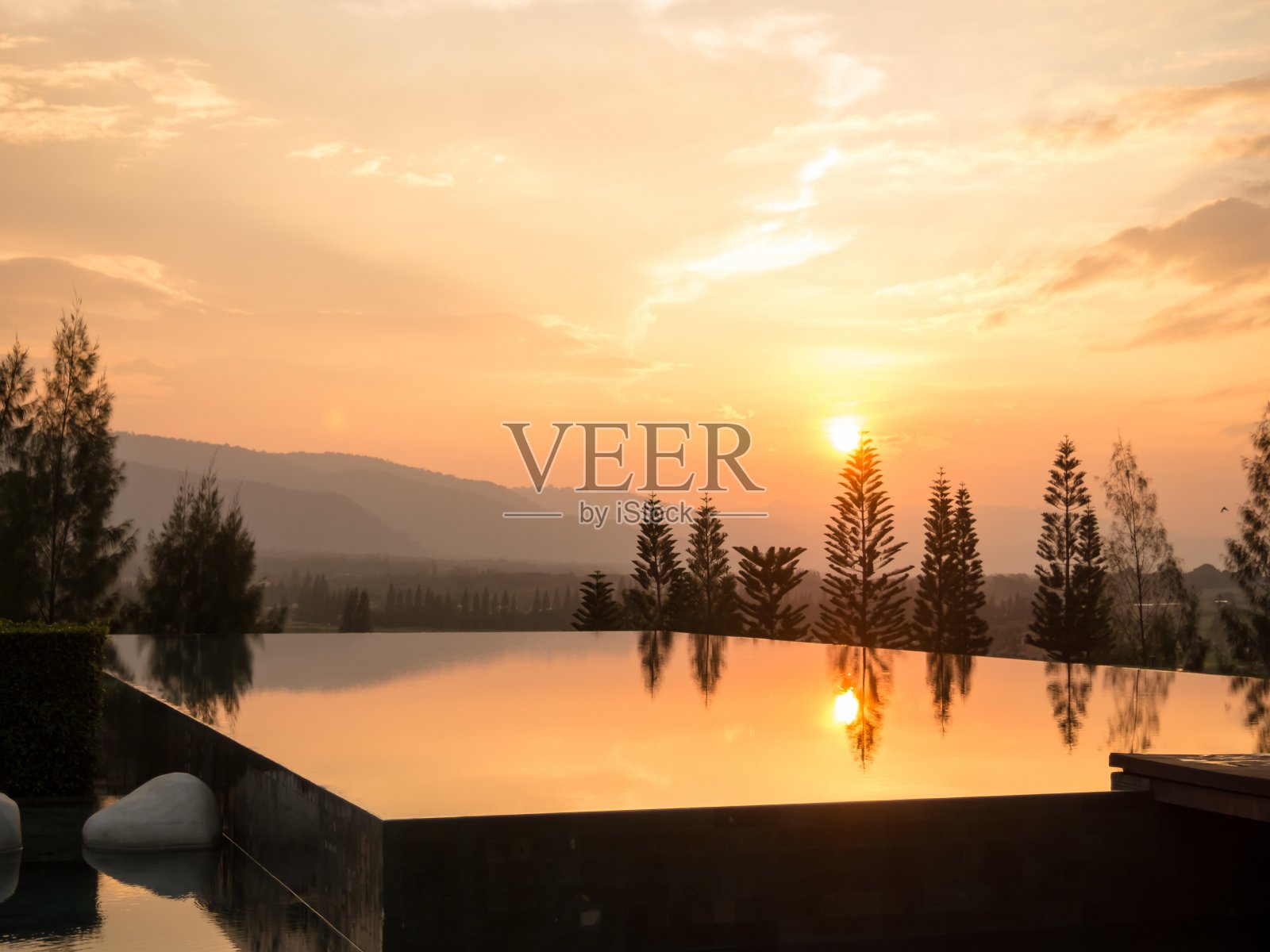 开放的游泳池与山的背景在日落。照片摄影图片