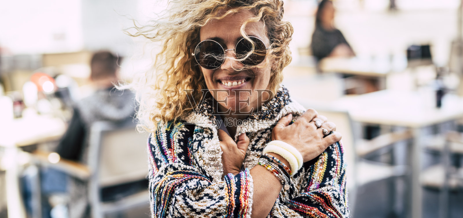 成年妇女户外肖像与散焦的人在背景-漂亮和愉快的年轻女性微笑和享受秋天的季节在城市的酒吧餐厅照片摄影图片