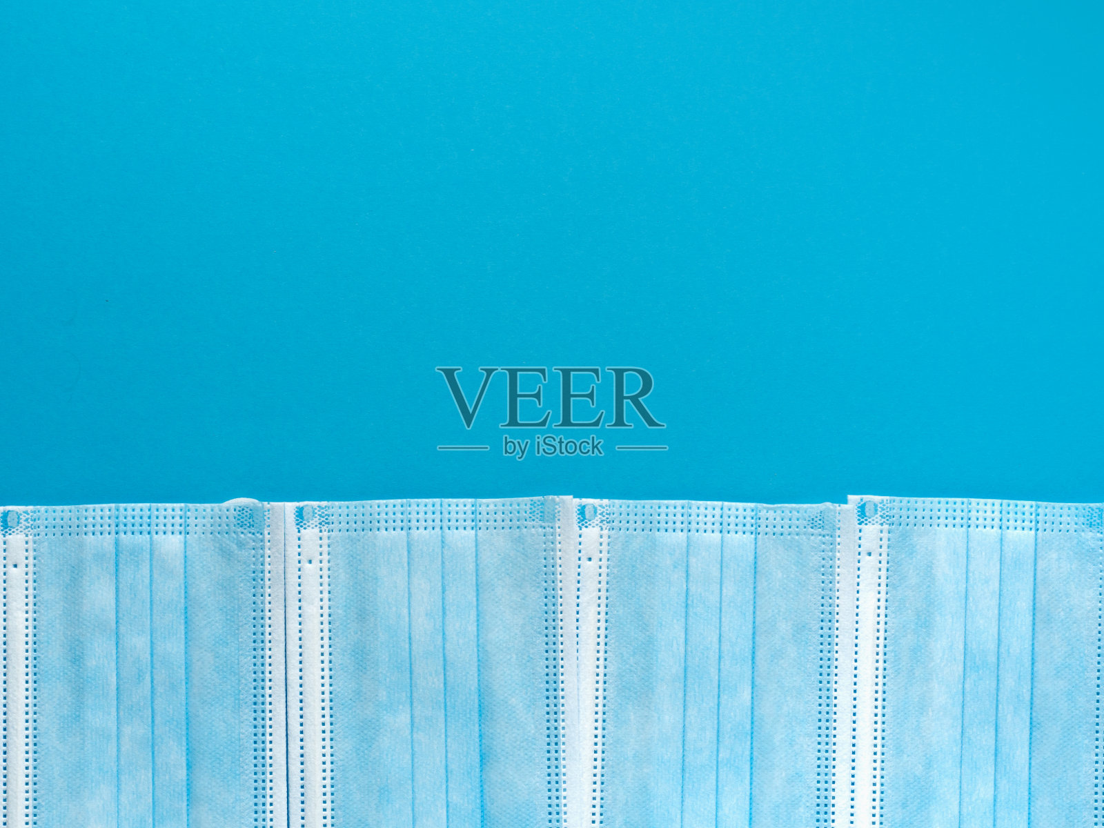 医用防护口罩以蓝色纸为背景。个人，一次性外科口罩平铺模式。检疫卫生保健和冠状病毒防护概念背景照片摄影图片