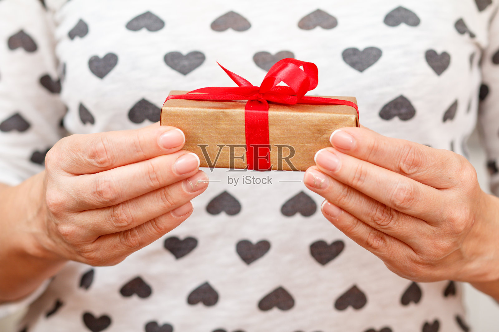 女人手里拿着一个用红丝带系着的礼盒照片摄影图片