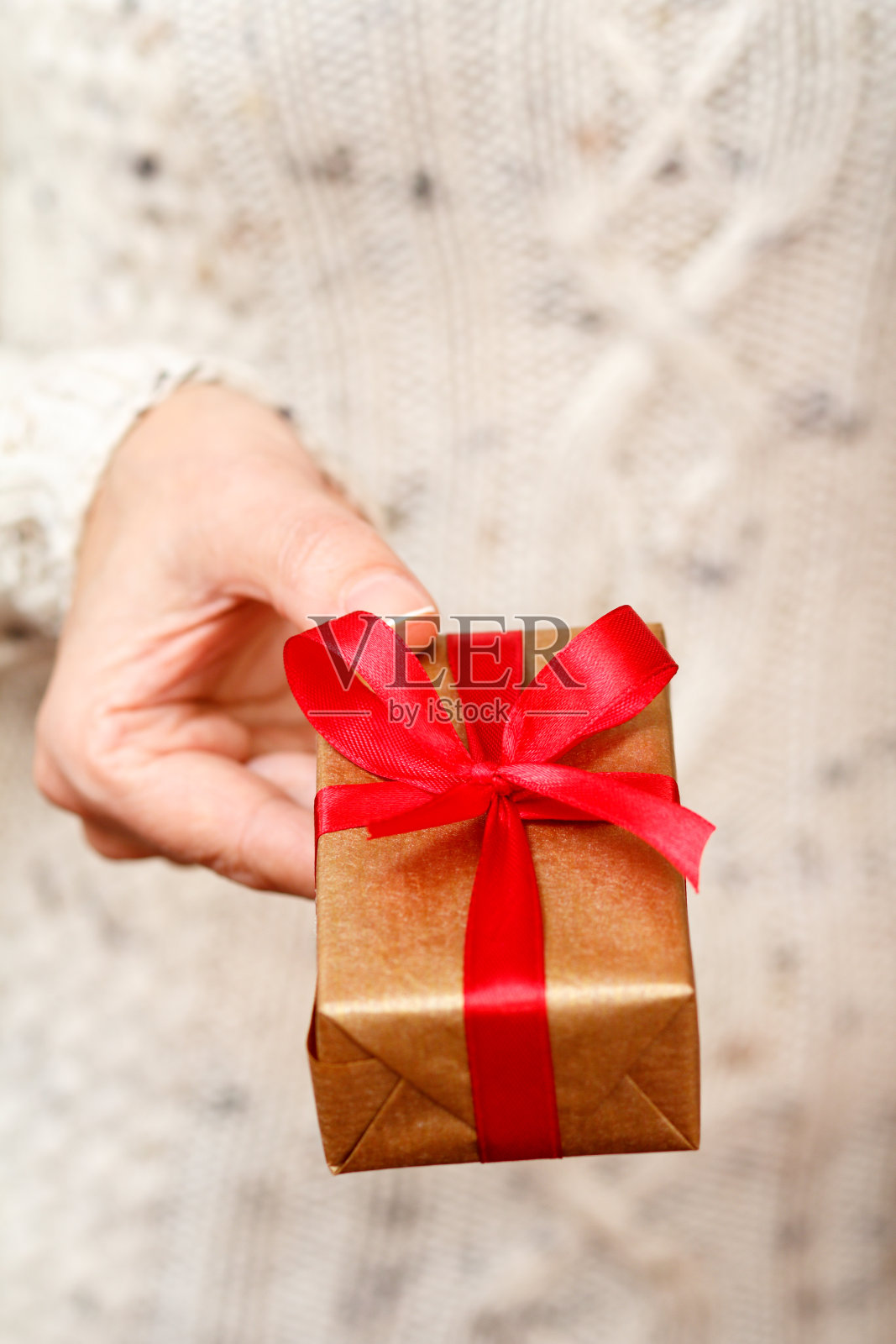 女人手里拿着一个用红丝带系着的礼盒。照片摄影图片
