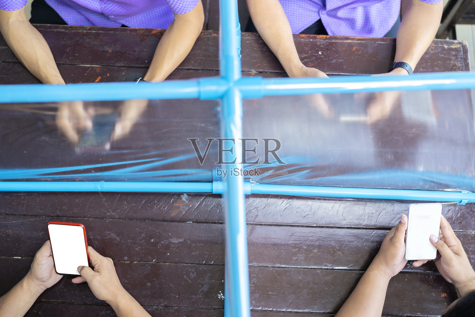 一群用智能手机隔开的人。为了阻止或减缓COVID-19冠状病毒的传播，隔离身体以进行感染控制的概念照片摄影图片